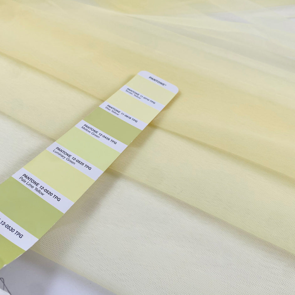 Polyester stretch tulle in light yellow color reference Tender Yellow. Very soft, light, and transparent, it adds volume and is ideal for dresses and skirts. High-quality deadstock collected in Stock from a Maison de Couture in Italy.