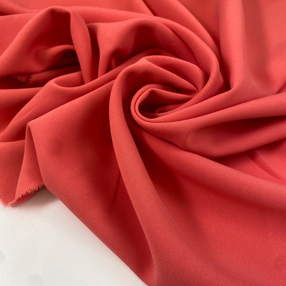 Polyester cady in calypso coral, very soft, flowy and with a matte finish. Ideal for trousers, skirts, dresses and jackets. High-quality deadstock collected in Stock from a Maison de Couture in Italy.