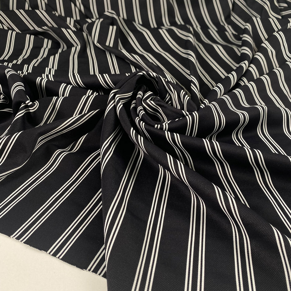 Black base Punto Milano polyester with double white lines. The fabric is stretch. High-quality deadstock collected in Stock from a Maison de Couture in Italy.