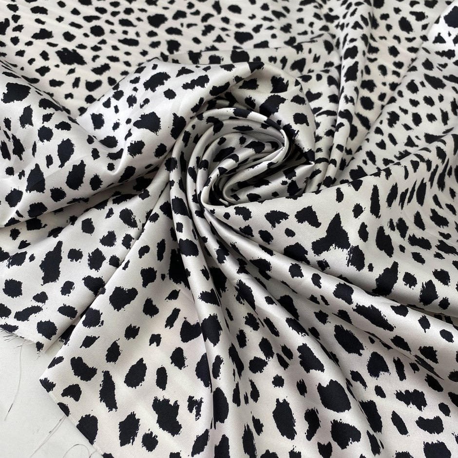 Polyester satin with stretch in black and white animal print. Shiny, very soft and light, flowy and not transparent. Ideal for dresses, skirts, blouses, and shirting. High-quality deadstock collected in Stock from a Maison de Couture in Italy.