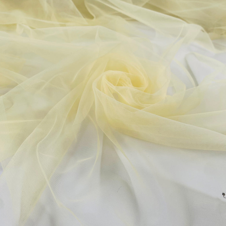 Polyester stretch tulle in light yellow color reference Tender Yellow. Very soft, light, and transparent, it adds volume and is ideal for dresses and skirts. High-quality deadstock collected in Stock from a Maison de Couture in Italy.