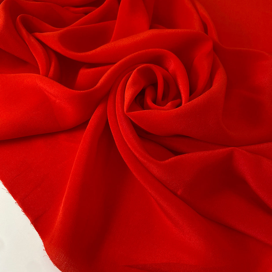Crepe de chine in red color reference flame scarlet. Very soft and light, flowy and not transparent. Ideal for dresses, skirts, blouses, and shirting. High-quality deadstock collected in Stock from a Maison de Couture in Italy.