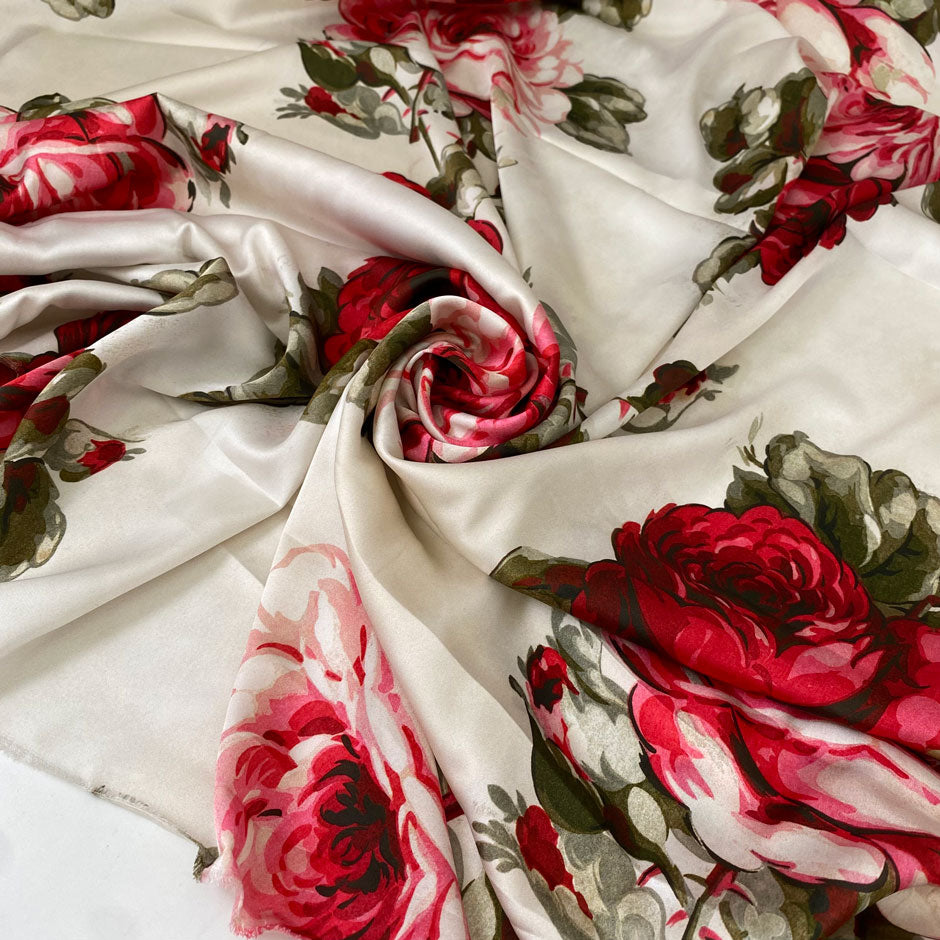 Polyester satin printed with a large floral design in shades of green, red, and fuchsia on an ivory background. Very soft and light, flowy, and ideal for dresses, blouses, shirting, and skirts. High-quality deadstock collected in Stock from a Maison de Couture in Italy.