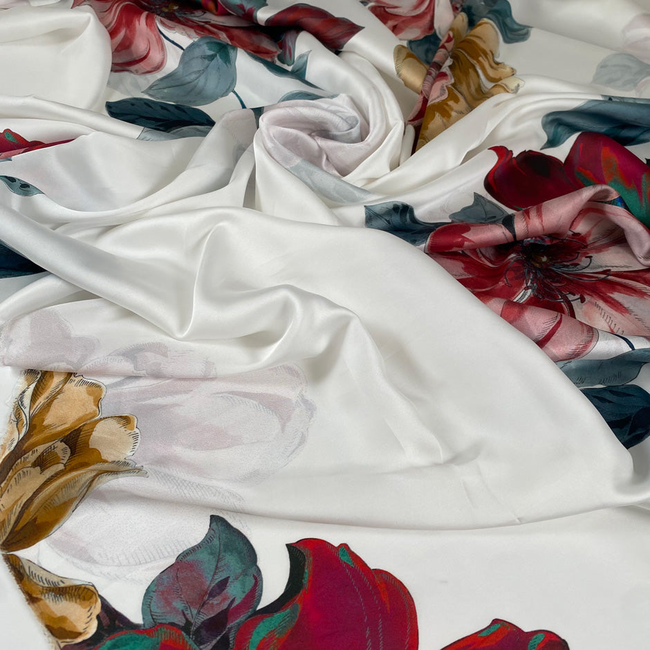 Polyester satin with a white base and large floral print in red, green, gray, pink, and beige. Light, flowy, slightly shiny, not transparent. High-quality deadstock collected in Stock from a Maison de Couture in Italy.