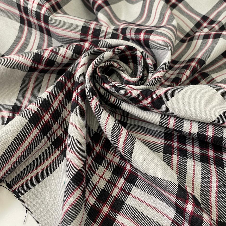 Soft and flowy polyester and viscose fabric with a check design in shades of gray and black, accented by subtle red stripes. Ideal for jackets, trousers, skirts, and dresses. High-quality deadstock collected in Stock from a Maison de Couture in Italy.