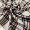 Soft and flowy polyester and viscose fabric with a check design in shades of gray and black, accented by subtle red stripes. Ideal for jackets, trousers, skirts, and dresses. High-quality deadstock collected in Stock from a Maison de Couture in Italy.