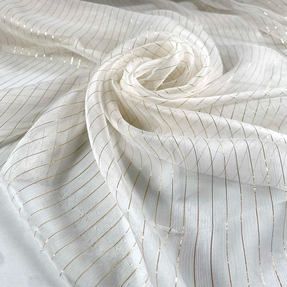 Pure silk chiffon in star white with golden lurex stripes. Very light, soft, flowy, and transparent. Ideal for dresses, skirts, blouses, and shirting. High-quality deadstock collected in Stock from a Maison de Couture in Italy.
