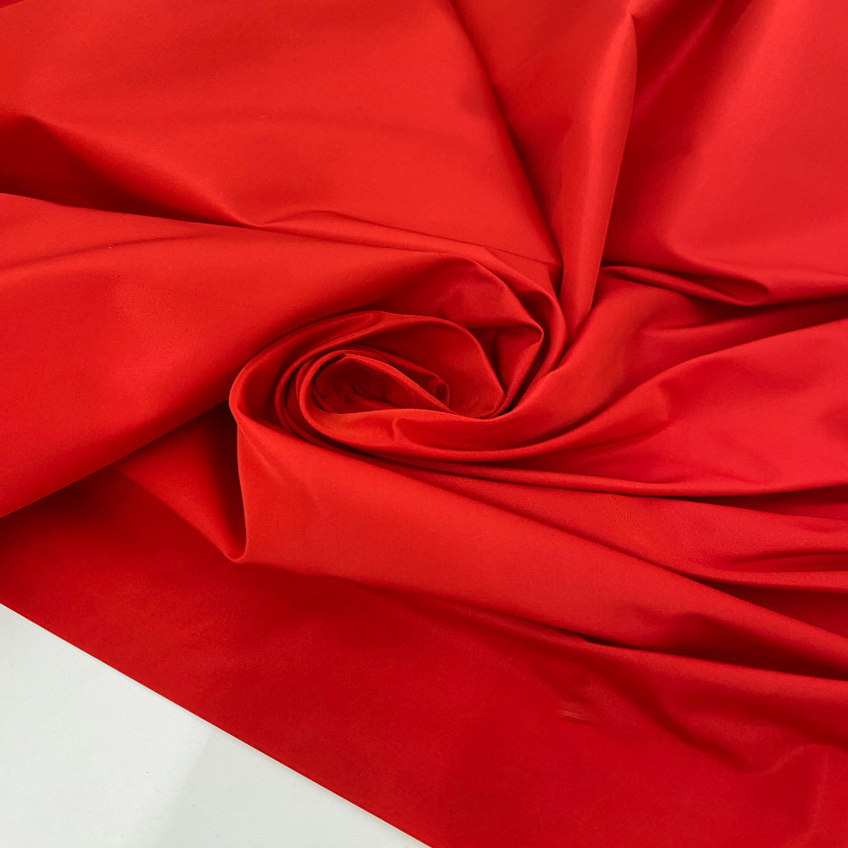 Silk and polyester taffeta in racing red. Light, crunchy, and structured. Keeps its shape.Ideal for skirts, dresses, and jackets. High-quality deadstock collected in Stock from a Maison de Couture in Italy.