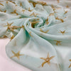 Pure silk chiffon with starfish pattern and light blue background. It is very soft, light and transparent. High-quality deadstock fabric by the meter collected in Stock from a Maison de Couture in Italy.