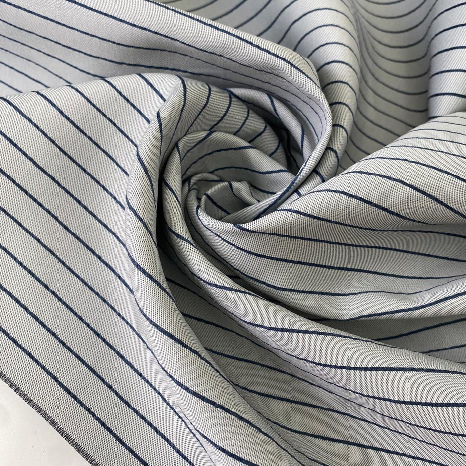 Heavy taffeta in a mix of polyester, silk, and cotton. Gray ground with blue stripes, heavy and stiff. Ideal for structured jackets, dresses, or skirts. High-quality deadstock collected in Stock from a Maison de Couture in Italy.