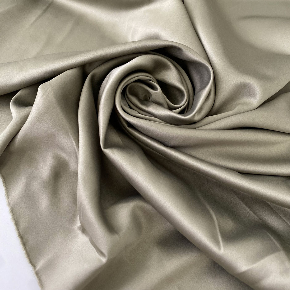 Polyester satin in sage green color reference elm. Very soft, light, and flowy with a matte finish. Not transparent. Ideal for dresses, skirts, and shirting. High-quality deadstock collected in Stock from a Maison de Couture in Italy.