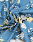 Light blue twill polyester in white and yellow floral design. The fabric is shiny and falling. High-quality deadstock fabric collected in Stock from a Maison de Couture in Italy.