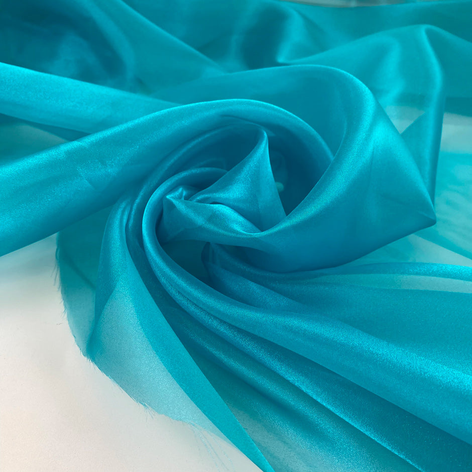 Polyester organza very shiny light and transparent, in bright turquoise. High-quality deadstock fabric collected in Stock from a Maison de Couture in Italy.