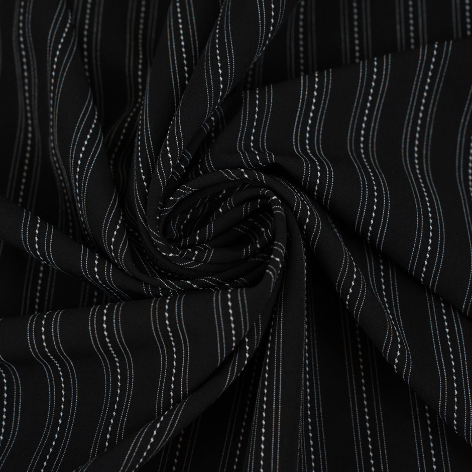 Fabric in black chalk stripe with fine white lines, elegant and slightly structured. Ideal for tailoring, trousers, jackets and skirts. High-quality deadstock collected in Stock from a Maison de Couture in Italy.