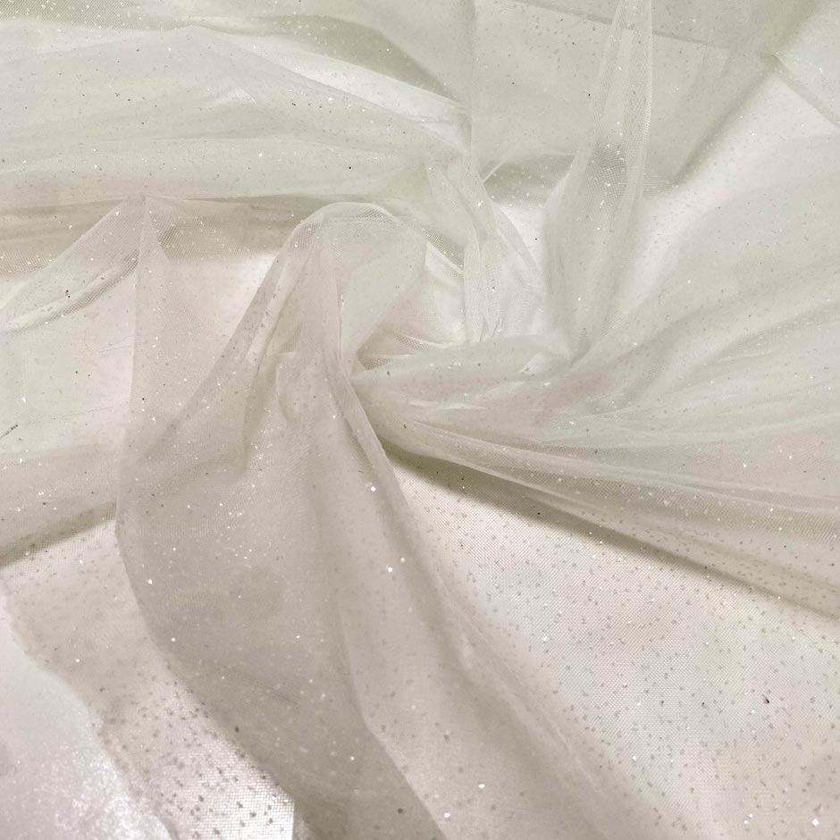 Soft polyester tulle in white with sparkling glitters. Light and delicate, perfect for dresses, skirts, blouses, and shirting.High-quality deadstock collected in Stock from a Maison de Couture in Italy.