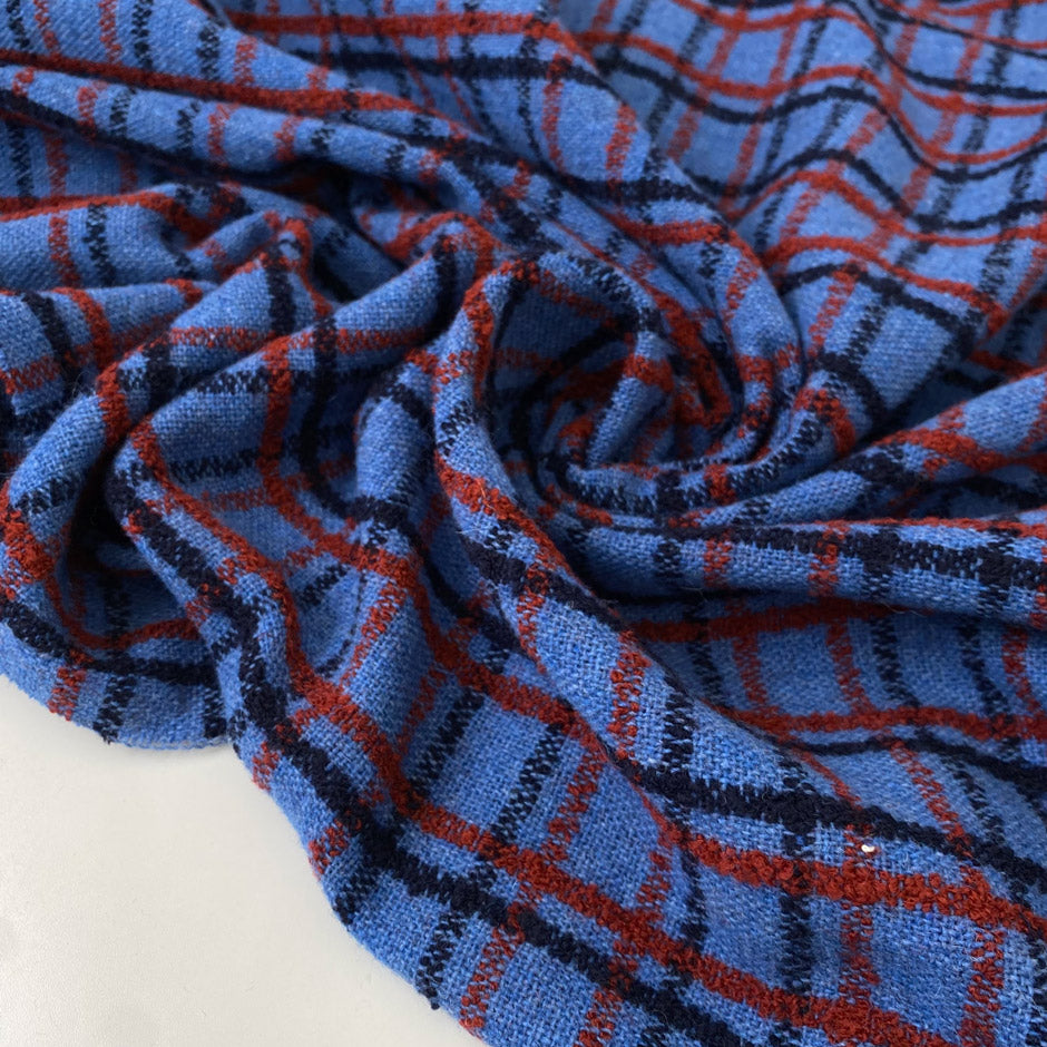 Pure wool twill with check pattern in blue red and dark blue shades blue jasper and molten lava soft and warm ideal for jackets light coats and winter skirts. High-quality deadstock collected in Stock from a Maison de Couture in Italy.